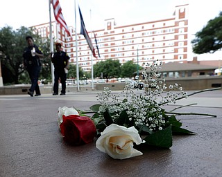 Dallas Police officers walk past roses left at the front doors of the station as part of a makeshift memorial, Friday, July 8, 2016, in Dallas. Five police officers are dead and several injured following a shooting during what began as a peaceful protest in the city the night before. (Eric Gay | AP Photo)