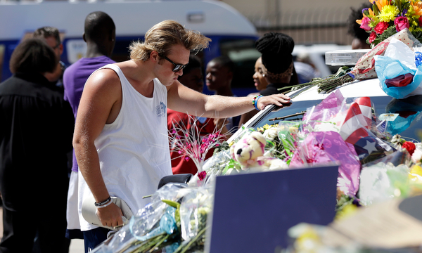A man pauses over a make-shift memorial at the Dallas police headquarters, Friday, July 8, 2016, in Dallas. Five police officers are dead and several injured following a shooting in downtown Dallas Thursday night. (Eric Gay | AP Photo)