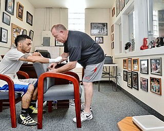Jeff Lange | The Vindicator SAT, JUL 9, 2016 - In an office full of boxing photos, John Loew of South Side Boxing wraps the hands of Popo Salinas (left) prior to the start of training at the gym on Market Street on Saturday, July 9, 2016.