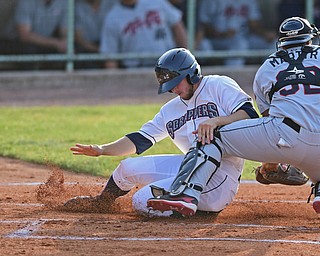 NILES, OHIO - JULY 11, 2016: Andrew Calica #26 of the Scrappers slides across home plate to score a run after catcher Kevin Martir #32 of the ValleyCats unsuccessfully plays the baseball, after a RBI double by Erlin Cerda #4 in the first inning of Monday nights game at Eastwood Field. DAVID DERMER | THE VINDICATOR