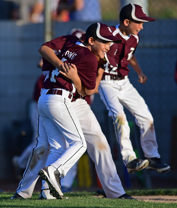 BOARD MAN, OHIO - JULY 15, 2016: Relief pitcher Charlie Young(4) of Boardman is hugged by teammate Gavin Hyde(2), while Matt Kay(42) leaps behind them after the conclusion of Friday evenings District 2 9/10 year old Little League Championship game at the Field of Dreams. Boardman would go on to win 18-5. DAVID DERMER | THE VINDICATOR