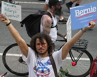 Nikos Frazier | The Vindicator..A protestor holds Sen. Bernie Sanders support signs while walking with other supporters down Broad St. towards the Wells Fargo Center on the first day of the Democratic National Convention in Philadelphia.