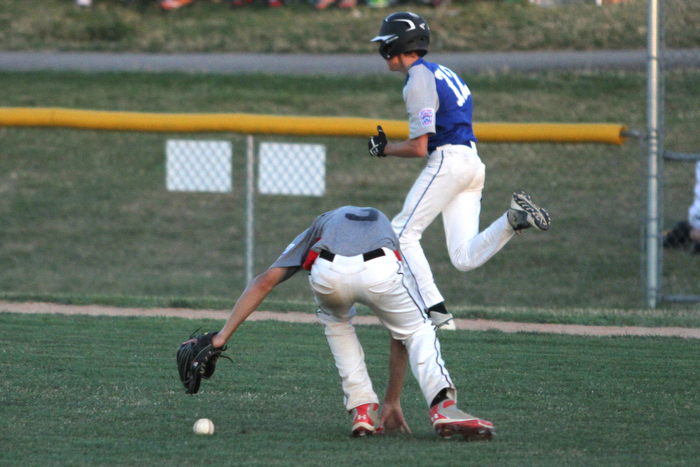 Nikos Frazier | The Vindicator..East Holmes' pitcher Brett Miller(3) fumbles with the ball as a Poland runner closes in on first during the Junior Little League State Championship game at the Fields of Dreams in Boardman.