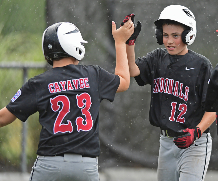 BOARDMAN, OHIO - JULY 29, 2016: Jake Schneider(12) of Canfield is congratulated by teammate Logan Cayavec after blasting a three run home run in the fourth inning of Friday evenings Little League game at the Fields of Dreams. Canfield would go on to win, 12-2.  DAVID DERMER | THE VINDICATOR