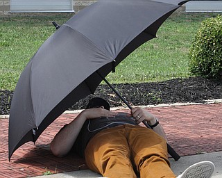 Nikos Frazier | The Vindicator..A man takes a nap under the protection of an umbrella outside of East High School before Democratic Presidential candidate Hillary Clinton spoke on Saturday night.