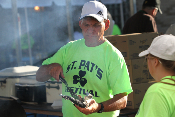 Nikos Frazier | The Vindicator..Fr. Mike Swierz loads a hoagie with meat at the St. Patrick Parish Festival in Hubbard.