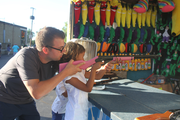 Nikos Frazier | The Vindicator..Georgianna Guzzo, 6, is helped by her father Matt Guzzo of Cranberry Township aim a riffle at prizes at the St. Patrick Parish Festival in Hubbard.