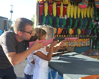 Nikos Frazier | The Vindicator..Georgianna Guzzo, 6, is helped by her father Matt Guzzo of Cranberry Township aim a riffle at prizes at the St. Patrick Parish Festival in Hubbard.