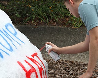 Nikos Frazier | The Vindicator..A student adds the word "Hate" to complete the "love trumps hate" message on the Rock outside the Kilcawley Center on Monday.