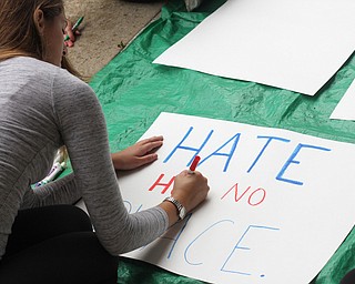 Nikos Frazier | The Vindicator..Kelly Dahman, a senior at YSU, writes "Hate has no place" sign outside the Kilcawley Center at the Youngstown State University.