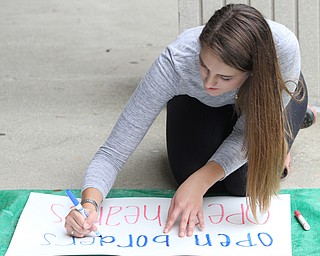 Nikos Frazier | The Vindicator..Kelly Dahman, a senior at YSU, writes "Open Borders, Open Hearts" sign outside the Kilcawley Center at the Youngstown State University.