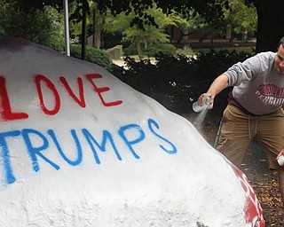 Nikos Frazier | The Vindicator..Jake Schriner-Briggs, a senior at YSU and member of the YSU College Democrats, uses white spray paint to cover the previous artists work on the Youngstown State Rock.