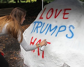 Nikos Frazier | The Vindicator..Kelly Dahman, a senior at YSU, writes "Love Trumps Hate" on the Youngstown State University Rock.