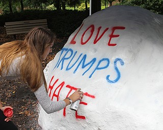 Nikos Frazier | The Vindicator..Kelly Dahman, a senior at YSU, writes "Love Trumps Hate" on the Youngstown State University Rock.