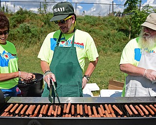 YOUNGSTOWN, OHIO - AUGUST 13, 2016: (LtoR) Lori Kibby of Columbiana, Scott Rodgers of Youngstown and Tom Davis of Austintown prepare hot dogs on the grill Saturday morning at the Covelli Center during the NOW Youngstown book bag giveaway. DAVID DERMER | THE VINDICATOR