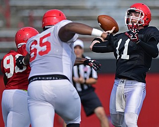YOUNGSTOWN, OHIO - AUGUST 20, 2016: Trent Hosick #11 (black) throws the deep pass while avoiding pressure from Joshmere Dawson #96 (red) after he got past Jason Sims #65 (white) during a scrimmage Saturday morning at Stambaugh Stadium. DAVID DERMER | THE VINDICATOR