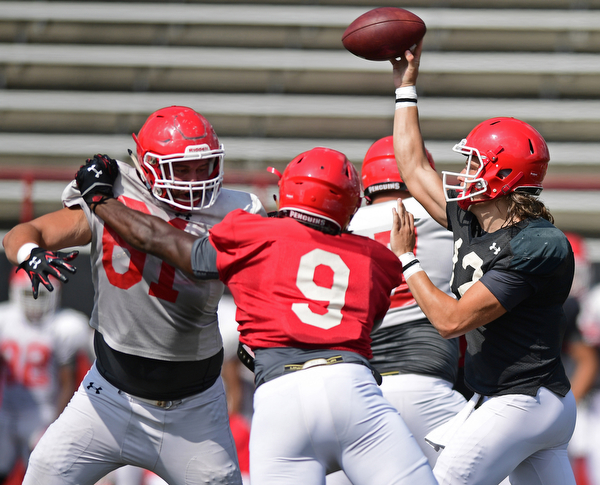YOUNGSTOWN, OHIO - AUGUST 20, 2016: Ricky Davis #12 (black) throws a pass from the pocket behind the block of Justin Spencer #61 (white) on I'tavious Harvin #9 (red) during a scrimmage Saturday morning at Stambaugh Stadium. DAVID DERMER | THE VINDICATOR