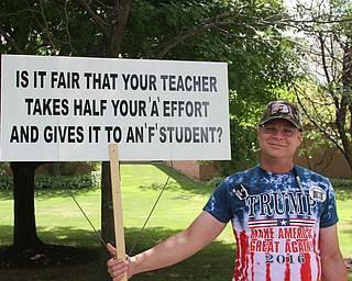 Nikos Frazier | The Vindicator..Mike of Cuyahoga Falls holds a "Is it fair that your teacher takes half your 'A' effort and gives it to an 'F' Student?" sign before Republican presidential candidate Donald Trump speaks at a campaign rally in Akron, Oh., Saturday, Aug. 20, 2016.