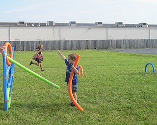 Neighbors | Alexis Bartolomucci.Children threw pool noodles through a hole for the javelin toss event as the Summer Olympics at the Austintown Community Church Preschool Childcare Center began on Aug. 5.