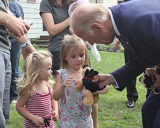 Nikos Frazier | The Vindicator..Vice President Joe Biden hands stuffed animals to two girls on Lanterman Ave. in Youngstown. The dog is replica of his dog, Champ.