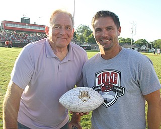 Nikos Frazier | The Vindicator..LeeRoy Lewis and Travis Stocker, Struthers High School Class of 1962 and 1990, pose for a photo with a 100-year anniversary commemorative football at the Laddie J. Fedor Field.