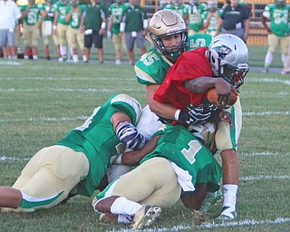 Youngstown East's Michael Lawrence (2) carries a few Ursuline defenders led by Daylen Harris (1) and Mario Fusillo (45) while stretching the ball across the goalline during the first quarter of Friday nights matchup at Rayen Field in Youngstown.