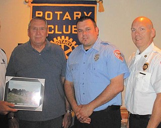 SPECIAL TO THE VINDICATOR
Special guests at the Aug. 28 meeting of Austintown Rotary included three firefighters of the Austintown Fire Department and a family member of Fireman John Fritz, who died in the line of duty in June.  The guests thanked the club for supplying 42 flags to line Winthrop Drive honoring Fritz at his funeral. Above, a plaque was presented to Ed Kalaher, left, club president, by Richard Fritz, the father of John Fritz. Firefighters joining them were Bill Palkovic, Mike McNally and Mike Smith. Below, Atty. Nils Johnson Sr. of Canfield, right, informed members and guests about the oil industry and shale drilling futures and their effect on the world market. Pictured with him are Kalaher, holding a library book that will be donated to Austintown Elementary School Library, and Atty. Nils Johnson Jr.
