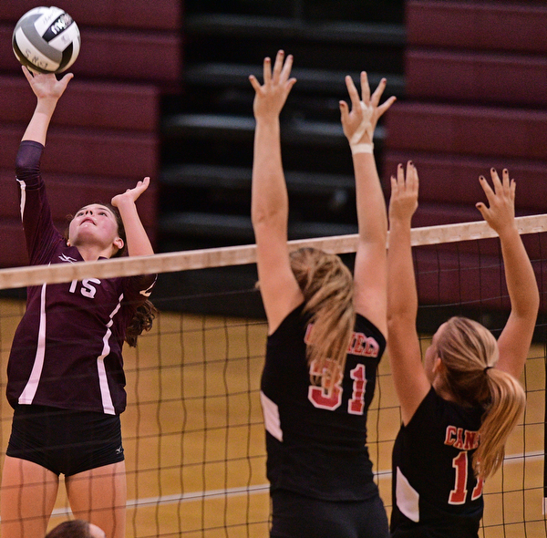BOARDMAN, OHIO - SEPTEMBER 20, 2016: Kaylin Burkley #15 of Boardman hits the ball over the net while Natalie Maras #31 and Alyssa Householder #11 of Canfield go for the block during the first set of their match Tuesday night at Boardman High School. DAVID DERMER | THE VINDICATOR