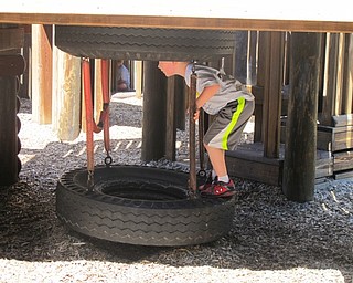 Neighbors | Alexis Bartolomucci.One of the children climbed in the tire tunnel at Boardman Park during the last day of Camp FRIEND on Aug. 26.