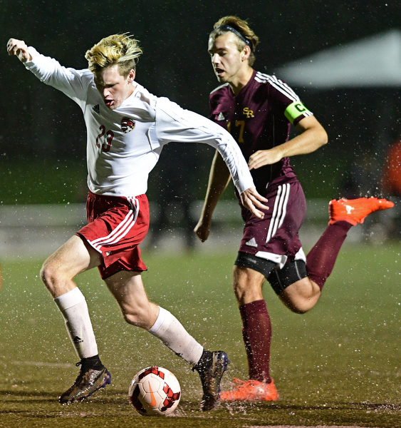 CANFIELD, OHIO - SEPTEMBER 29, 2016: RJ Thomas #23 of Canfield moves the ball through a puddle while being chased by Mitch McConnell #17 of South Range during the first half of their game Thursday night at Canfield High School. DAVID DERMER | THE VINDICATOR