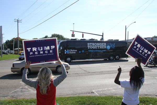 Nikos Frazier | The Vindicator..Trump supporters hold up "Trump Pence" signs as Former President Bill Clinton's bus passes them after leaving the Trumbull County Hillary for America offices in Warren .