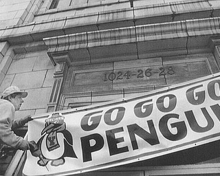 GO PENGUINS-MARK BROWN, OWNER OF IMPACT SIGNS IN YOUNGSTOWN PUTS A GO PENGUINS SIGN UP IN FRONT OF THE OLD WARDS BAKERY ON MAHONING AVE. THE SIGN WAS BOUGHT BY PAUL MAHIN OF POSTAL MAIL-SORT INC. AND TERRY THOMAS OF SPECIAL BUSING. THE SIGNS ARE AVAILABLE FROM IMPACT FOR $49.95. 12/12/91