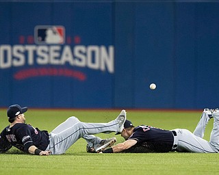 Cleveland Indians right fielder Lonnie Chisenhall, right, and second baseman Jason Kipnis (22) nearly collide as they slide for a single hit by Toronto Blue Jays' Russell Martin during the fifth inningn Game 5 of baseball's American League Championship Series in Toronto, Wednesday, Oct. 19, 2016. (Mark Blinch/The Canadian Press via AP)