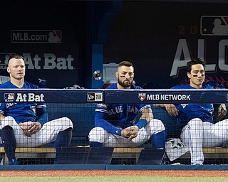 Toronto Blue Jays', from left, Josh Donaldson, Kevin Pillar and Darwin Barney watch from the dugout during the seventh inning in Game 5 of baseball's American League Championship Series against the Cleveland Indians in Toronto, Wednesday, Oct. 19, 2016. (Mark Blinch/The Canadian Press via AP)