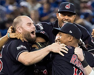 /Cleveland Indians' Mike Napoli, left, Coco Crisp, top, and Jose Ramirez, bottom right, celebrate with teammates after the team's 3-0 win over the Toronto Blue Jays in Game 5 of the baseball American League Championship Series in Toronto on Wednesday, Oct. 19, 2016. (Mark Blinch/The Canadian Press via AP)