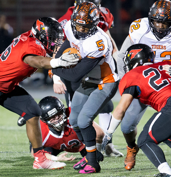 MICHAEL G TAYLOR | THE VINDICATOR- 10-21-16- 1st qtr, Howland's #5 Tyriq Ellis holds on to the ball as  Canfield's #56 Ron Williams makes the tackle. Howland Tigers vs Canfield Cardinals at Bob Dove Field in Canfield, OH.