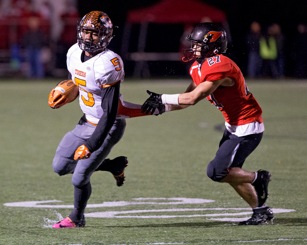 MICHAEL G TAYLOR | THE VINDICATOR- 10-21-16- 1st qtr, Howland's #5 Tyriq Ellis runs for a 1st down as   Canfield's #27 Paul French tracks him down. Howland Tigers vs Canfield Cardinals at Bob Dove Field in Canfield, OH.