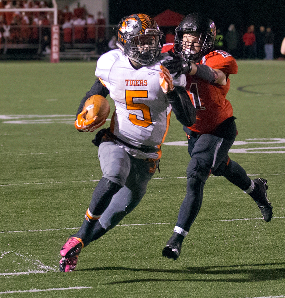 MICHAEL G TAYLOR | THE VINDICATOR- 10-21-16- 1st qtr, on his way to a 31 yard TD run, Howland's #5 Tyriq Ellis breaks the tackle of Canfield's #11 Will Dawson. Howland Tigers vs Canfield Cardinals at Bob Dove Field in Canfield, OH.