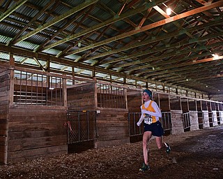 BAZETTA, OHIO - OCTOBER 22, 2016: Anna Guerra of McDonald sprints to the finish line through a horse barn to the finish line during the girl's Division 3 district cross country meet at the Trumbull Country Fairgrounds Saturday afternoon. DAVID DERMER | THE VINDICATOR