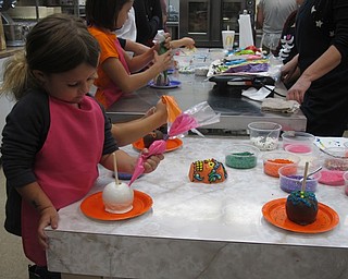 Neighbors | Alexis Bartolomucci.One of the children decorated her caramel apple with icing during the edible activity day on Oct. 15 at the Sugar Showcase in Austintown.