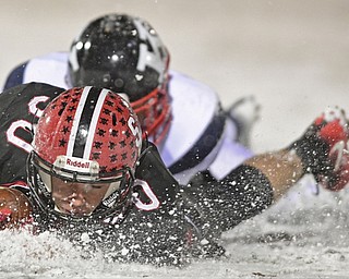 STRONGSVILLE, OHIO - NOVEMBER 19, 2016: Kurt Maxwell #30 of Norwalk St. Paul slides in the snow after being tackled by Joe Millard #32 of JFK during the first half of their playoff game Saturday night at Strongsville High School. DAVID DERMER | THE VINDICATOR