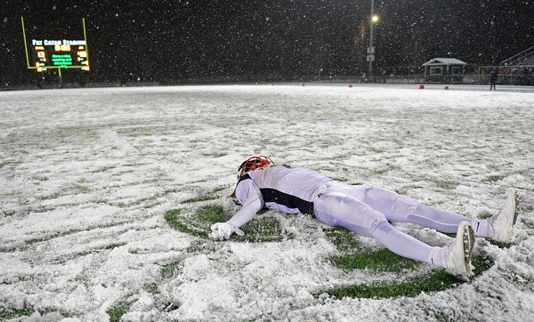 STRONGSVILLE, OHIO - NOVEMBER 19, 2016: Evan Boyd #7 of JFK makes a snow angel in the snow on the field after JFK won 48-13 over Norwalk St. Paul. DAVID DERMER | THE VINDICATOR
