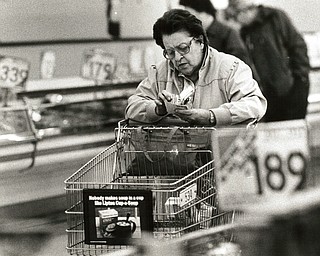 November 26, 1986 -- Shopping and saving top list of pre-Thanksgiving tasks..Money saver: Ernestine Simcox of Austintown looked over her coupons while shopping at CarlÕs. When preparing a dinner for 11, she found the coupons are a sure way of shaving expenses of what can becoe a costly event. (The Vindicator/ Bob DeMay)