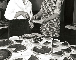 Novmeber 25, 1986 -- Annual 'feast' attracts many who are in need..The line formed early -- some showed up as early as 90 minutes before hand -- as First Presbyterian Church of Youngstown held its annual "Thanksgiving Celebration" feast for needy residents of the area. In all, 627 people came to enjoy a free ham dinner Tuesday afternoon at the church, Wick Avenue at Wood Street. Among the trimmings was pumpkin pie, being dished up by, at left: Ginny Jones, chairman for the dinner, and Dulcie Irving, church membership secretary. Musical entertainment was added to the festivities this year, and buses provided free transportation to the church from a variety of location around the city,. Funding for the meal is provided entirely by donations from church members, who also prepare and serve the food. Last year, more than 700 partook of the free dinner...The Vindicator/ Choo H. Ng
