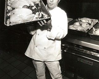 November 26, 1986 -- Poultry in the pan and the soup will make holiday diners happy..Paul Kakavros, a chef at AntoneÕs II in Boardman, displays just three of 60 turkeys he and his staff began roasting at about 3 a.m. this morning for the restaurantÕs Thanksgiving Day patrons.  (The Vindicator/ Patricia L. Fife)