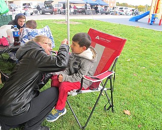 Neighbors | Alexis Bartolomucci.A Fitch high school student painted a football on one of the children's faces during the Junk in Your Trunk sale at Austintown schools on Oct. 22.