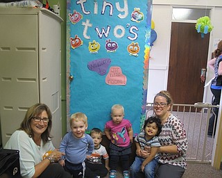 Neighbors | Alexis Bartolomucci.The Tiny Two's sat with Pattie Welsh and Shannon in front of the decorated door of the new toddler room at Hitchcock Woods Preschool.