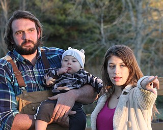 PHOTO BY NIKOS FRAZIER...Jessica Bush points at a group of turkeys as her partner, Seth Sharp, and their son Lincoln look on at Premium Pastured Meats' farm. The couple raise free-range animals on their Alliance farm that provide organic, non-GMO, pasture-fed beef, pork and turkey.