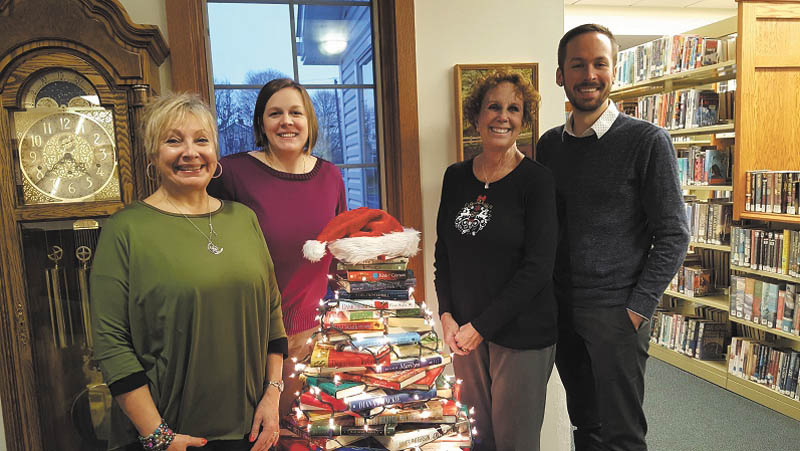 Leetonia Community Public Library recently welcomed Christopher Simmons as a new employee. Joan Clunen and Linsday Kuzemchak created a book tree to decorate for the holidays. The library will host Santa at 5 p.m. Saturday after he rides into Wick Park on a fire truck to light the tree. Cookies and cocoa will be served during Santa’s visit by Friends of the Library. From left are Clunen, Kuzemchak, Judy Kiliany and Simmons. SPECIAL TO THE VINDICATOR