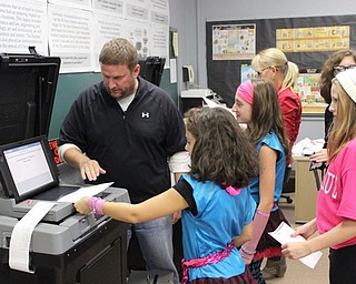 Neighbors | Abby Slanker.Canfield Village Middle School teacher Jason Jugenheimer helped students feed their completed ballots into an electronic voting machine during the school’s mock presidential election Oct. 28.